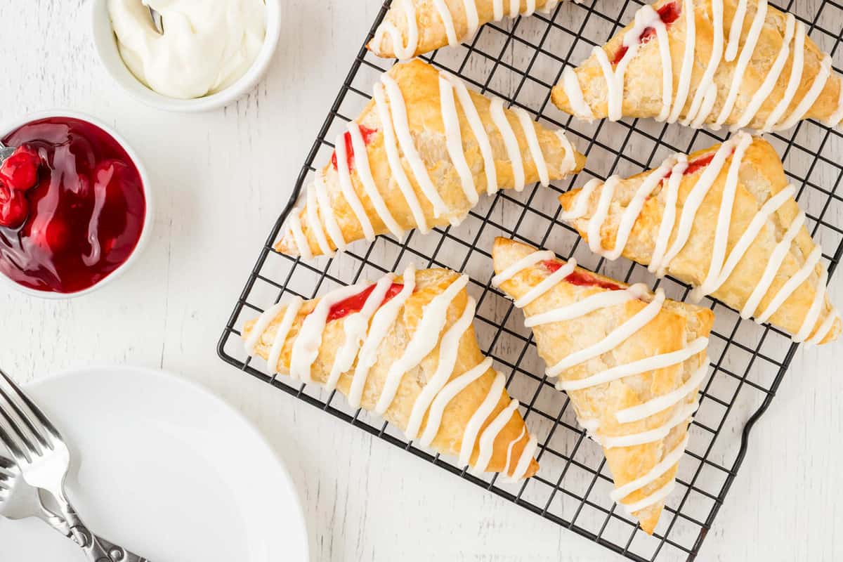 Homemade Cherry Turnovers Overhead Image on Cooling Rack with Bowl of Cherry Pie Filling