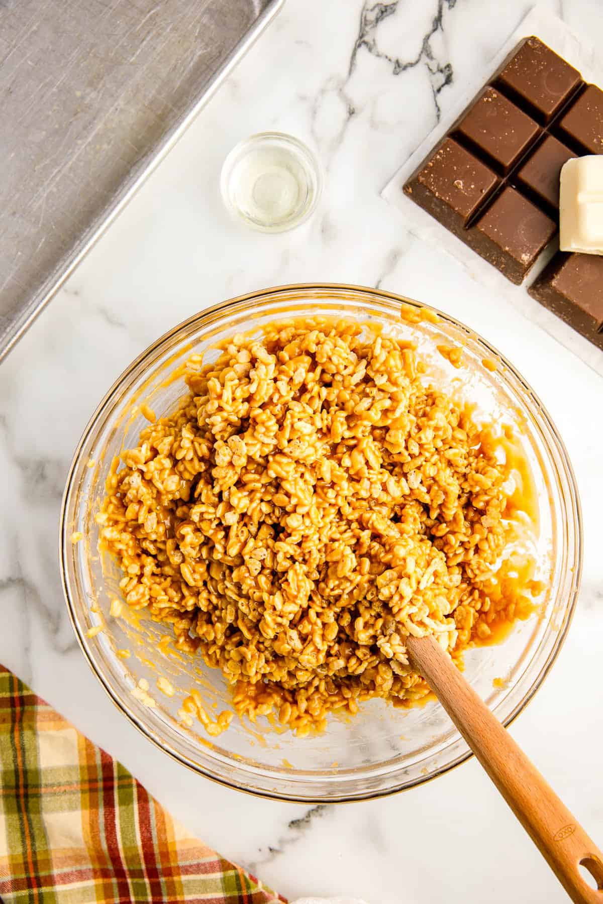 Cereal blended with peanut butter mixure in bowl with wooden spoon