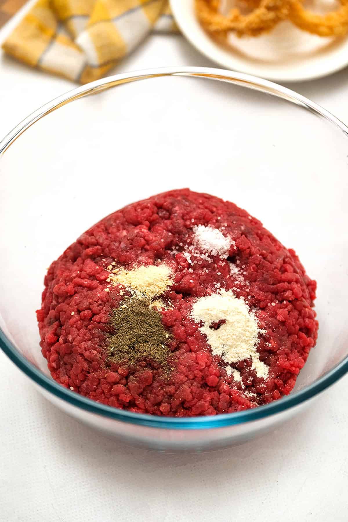 Combining Ground Beef and Seasonings in Mixing Bowl