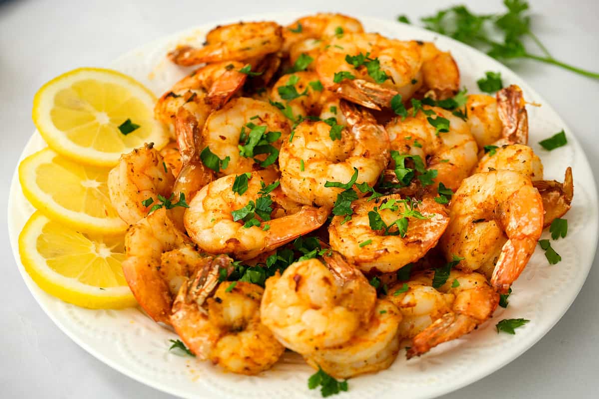 White plate with lemon slices and cooked shrimp