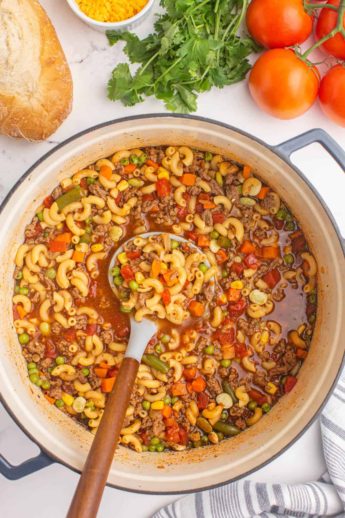 Stirring Hamburger Macaroni Soup in Dutch Oven