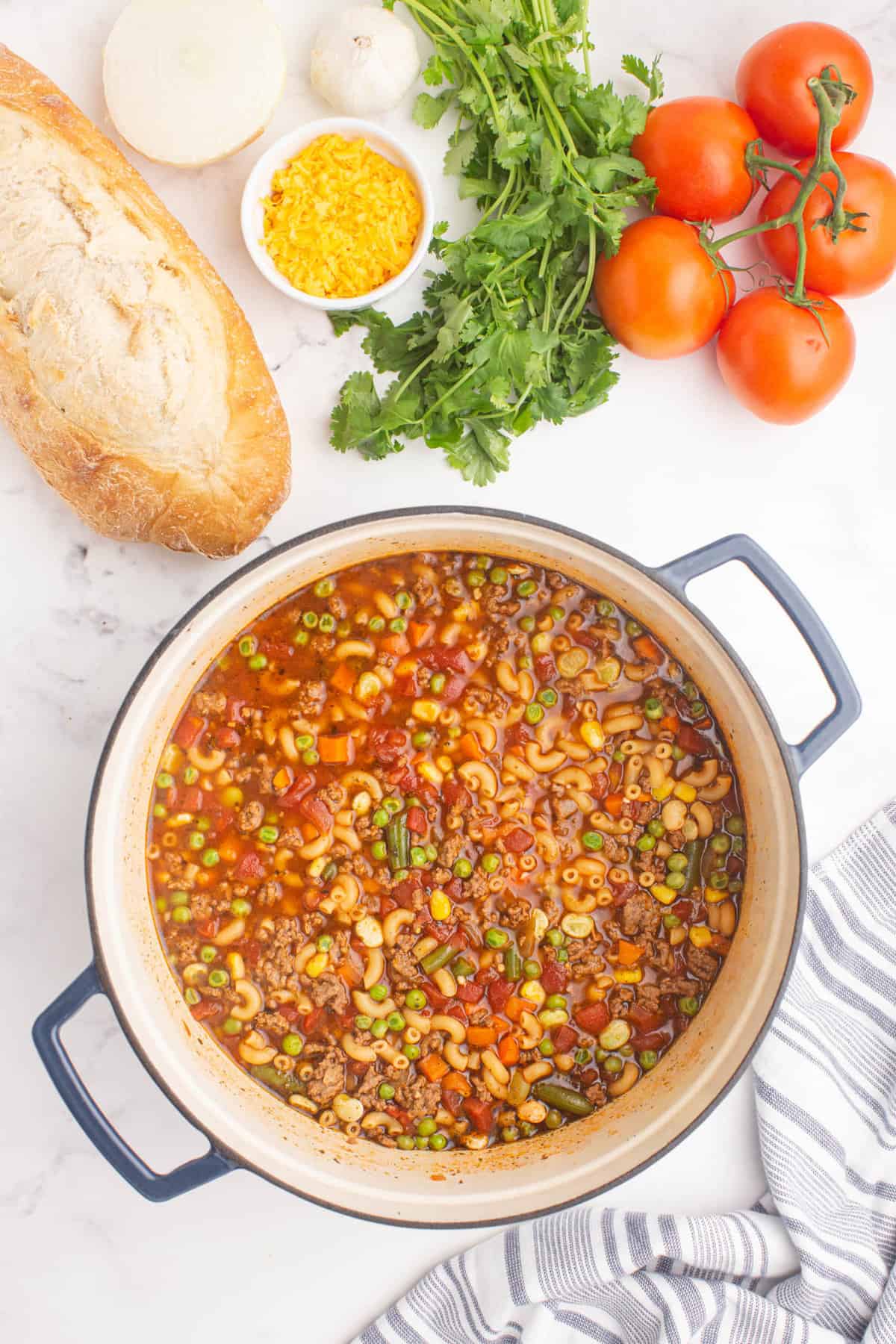 Simmering Ingredients for Tomato Beef Macaroni Soup in Dutch Oven