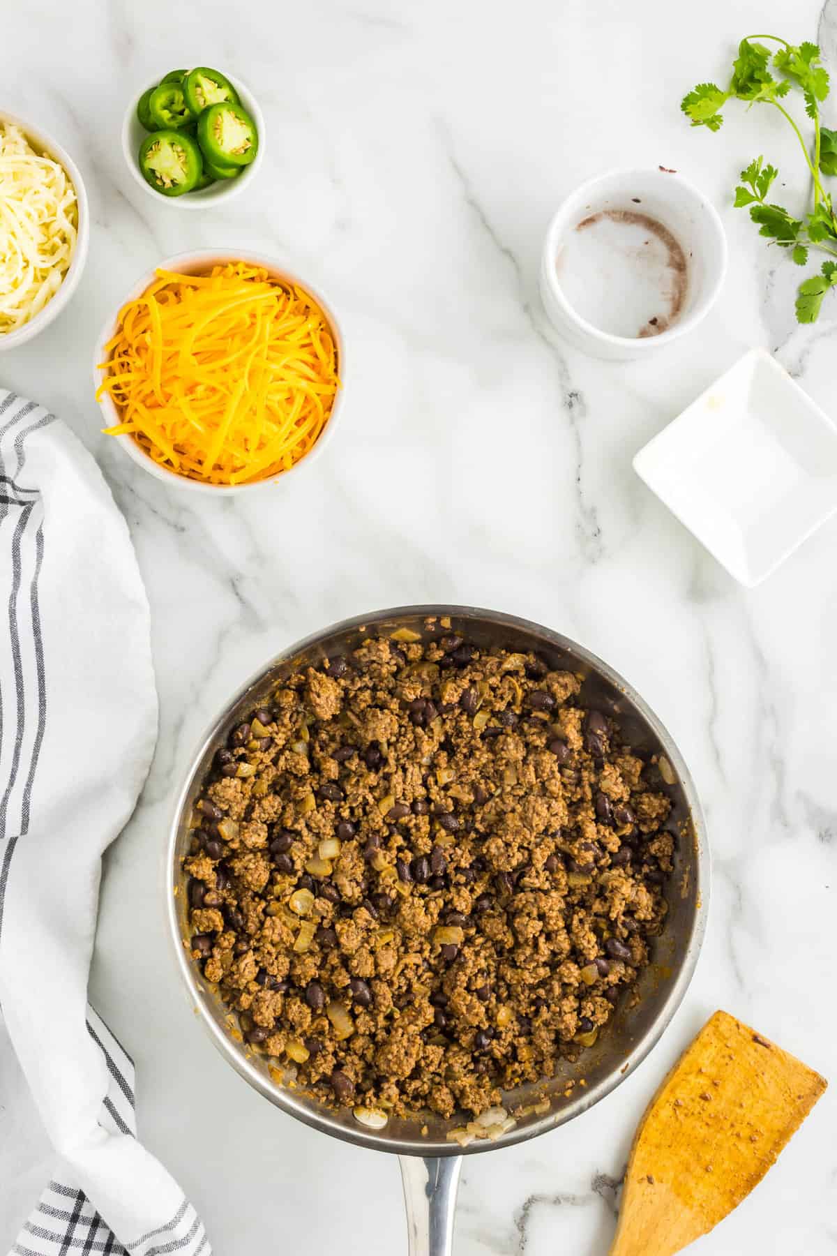 Adding in Taco Seasoning, Water, and Black Beans to Ground Beef for Loaded Nacho Recipe