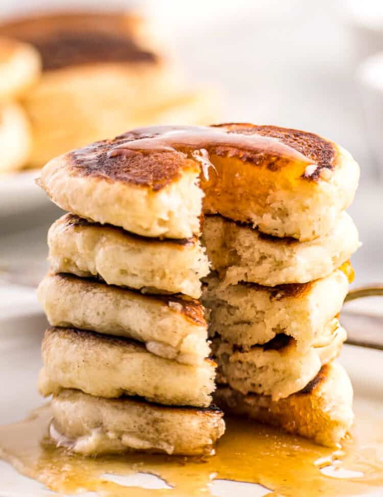 White plate with mini pancakes covered in syrup