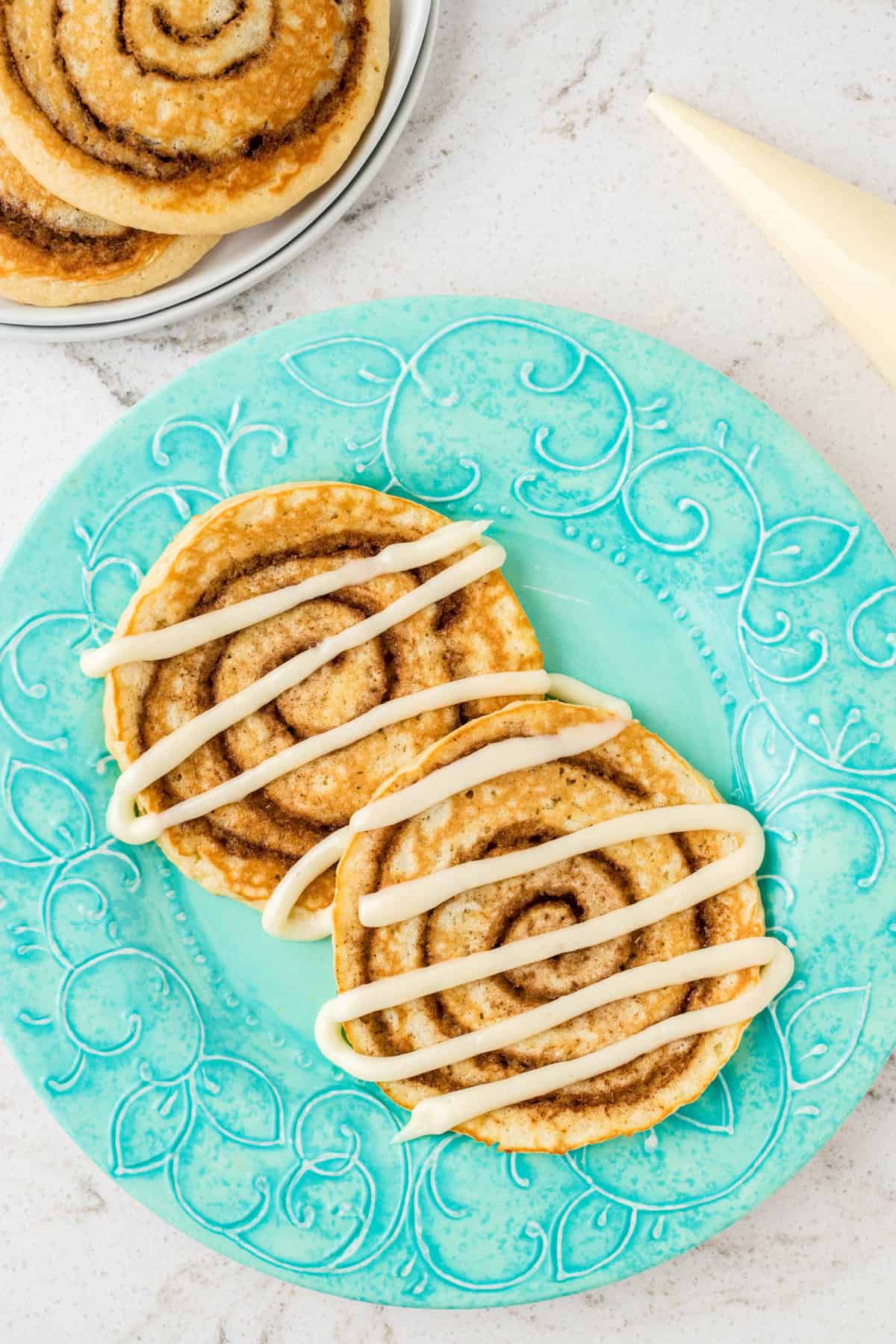 Cinnamon Roll Pancakes Drizzled with Cream Cheese Icing Plated and Ready to Enjoy