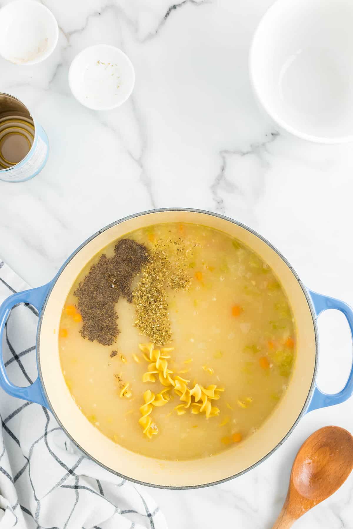 Adding Seasoning and Uncooked Egg Noodles to Homemade Creamy Chicken Noodle Soup Recipe