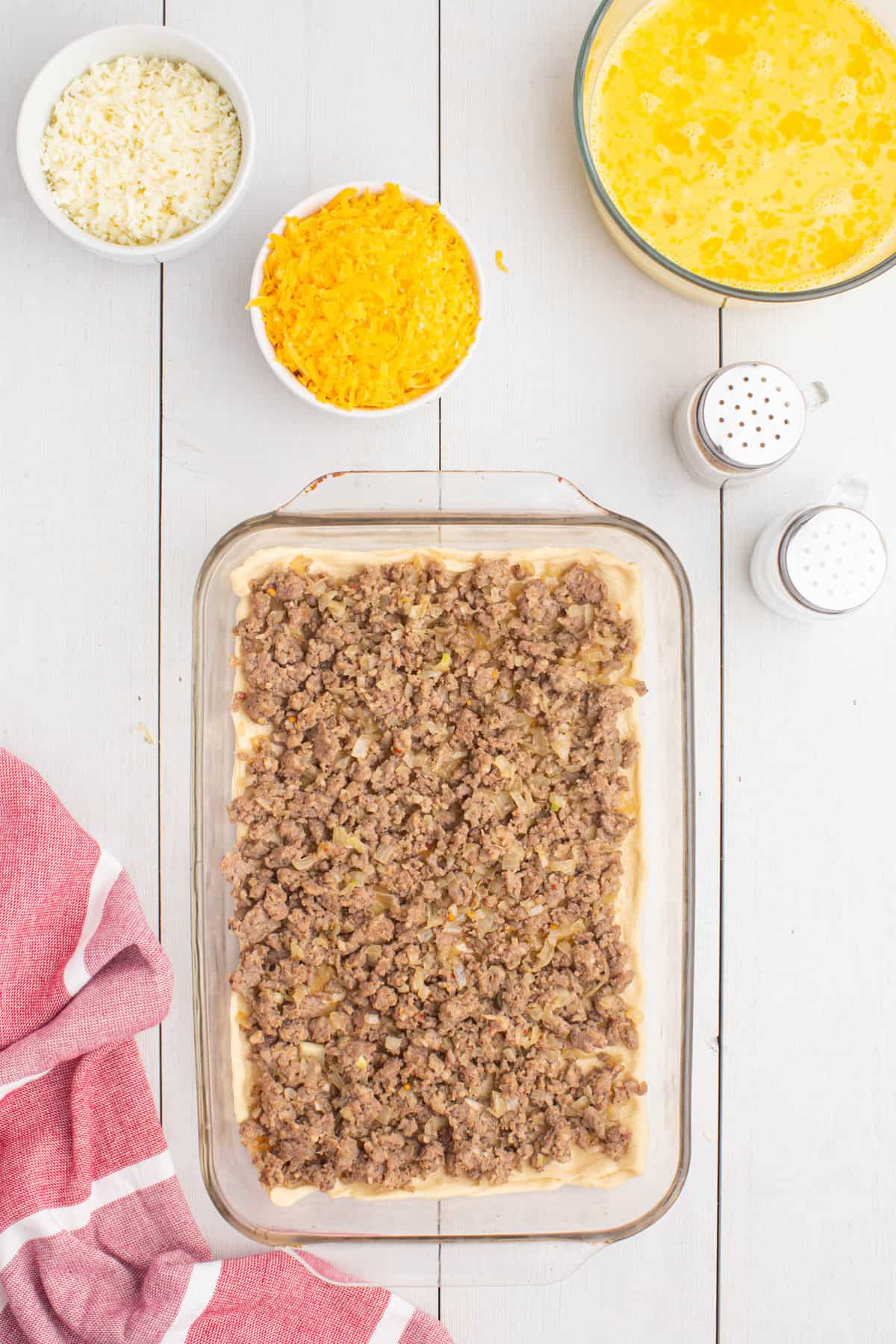 Topping Crescent Rolls with Browned Sausage in 9x13 Baking Dish for Crescent Roll Breakfast Bake