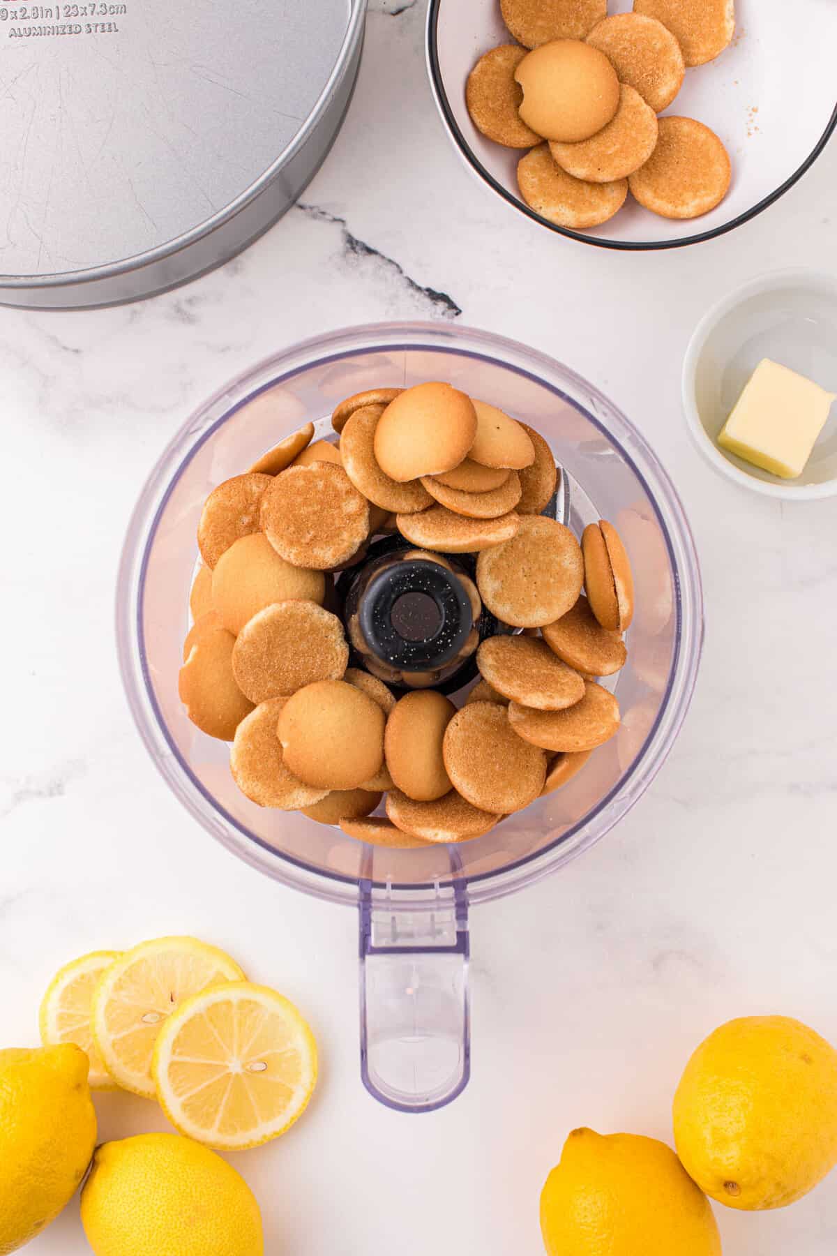 Adding Vanilla Wafer Cookies to Food Processor for Lemon Meringue Cheesecake Recipe