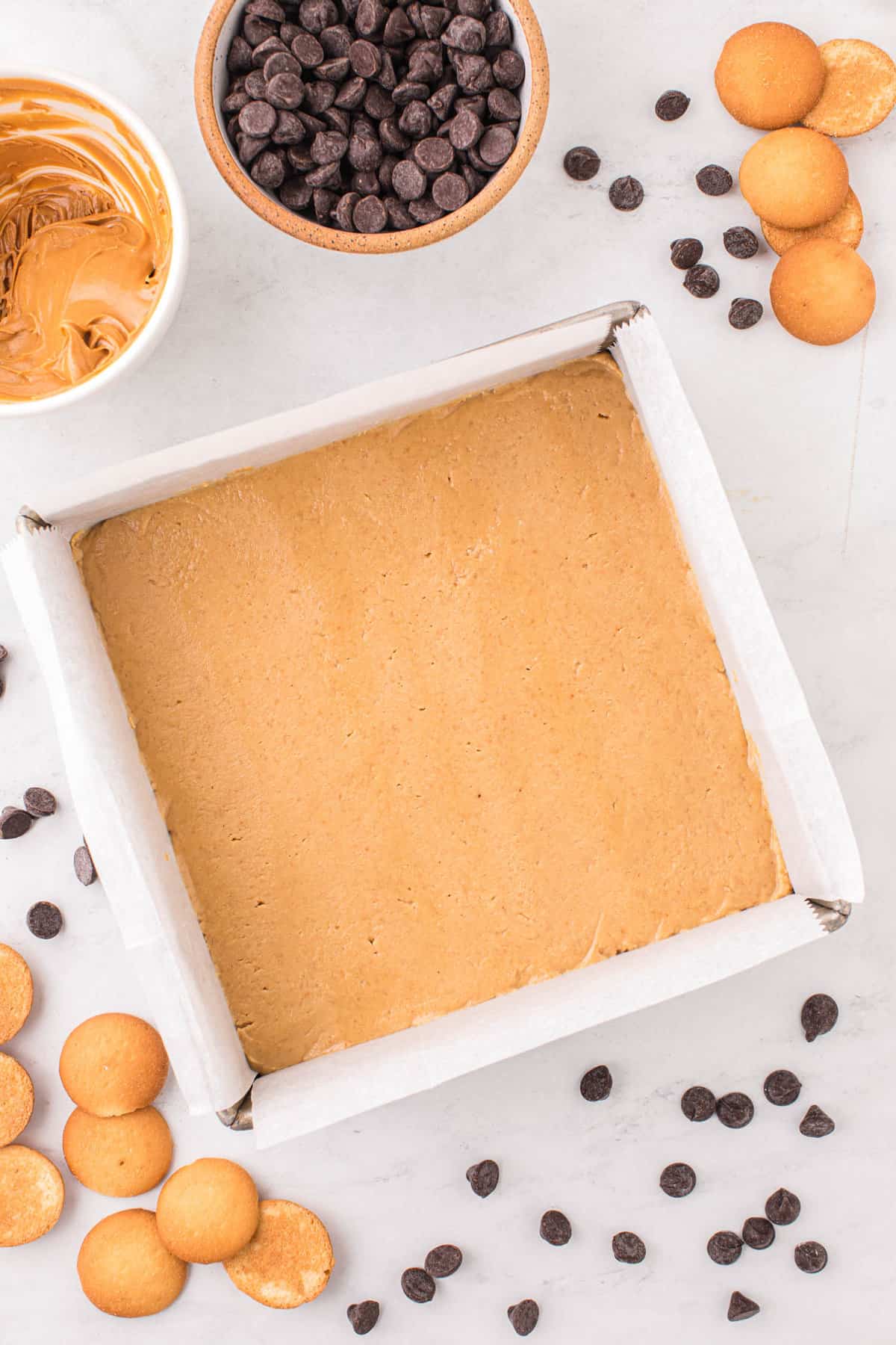 Pressing Peanut Butter Mixure into Parchment-Lined Square Pan for Chocolate Peanut Butter Bars