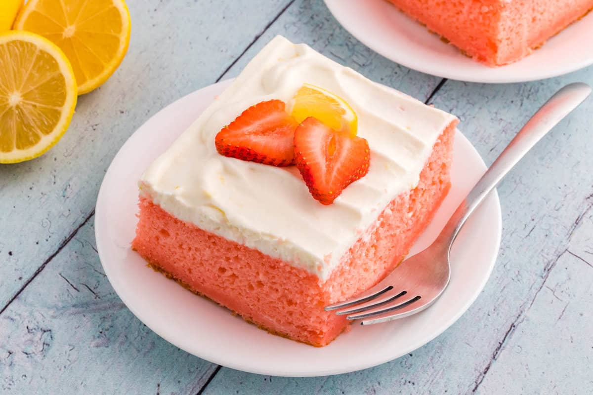 Strawberry Lemon Cake Recipe on a Pate Topped with Fresh Strawberries and Lemons for Garnish