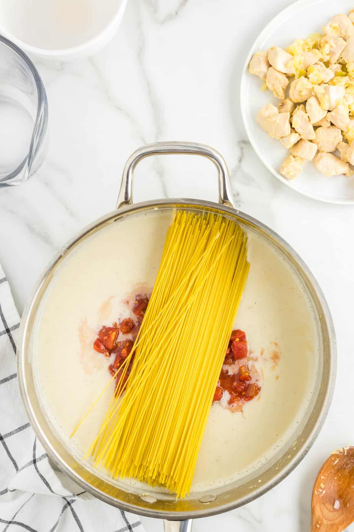 Adding Roltel and Angel Hair Pasta to Stovetop Pot for One Pot Chicken Spaghetti Recipe