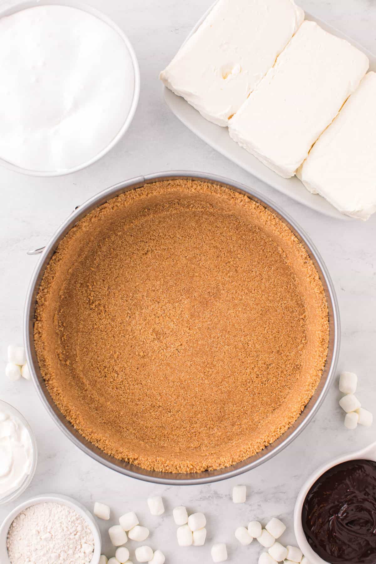 Pressing Graham Cracker Crust into Springform Pan for Smores Cheesecake Recipe