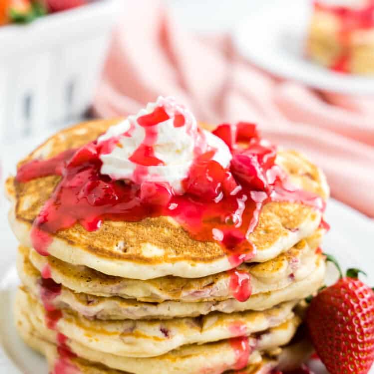 Strawberry Pancake Recipe on Plate Topped with Strawberry Syrup and Whipped Cream