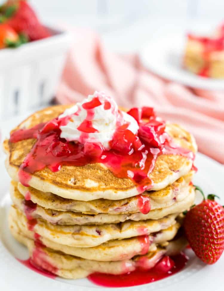 Strawberry Pancake Recipe on Plate Topped with Strawberry Syrup and Whipped Cream