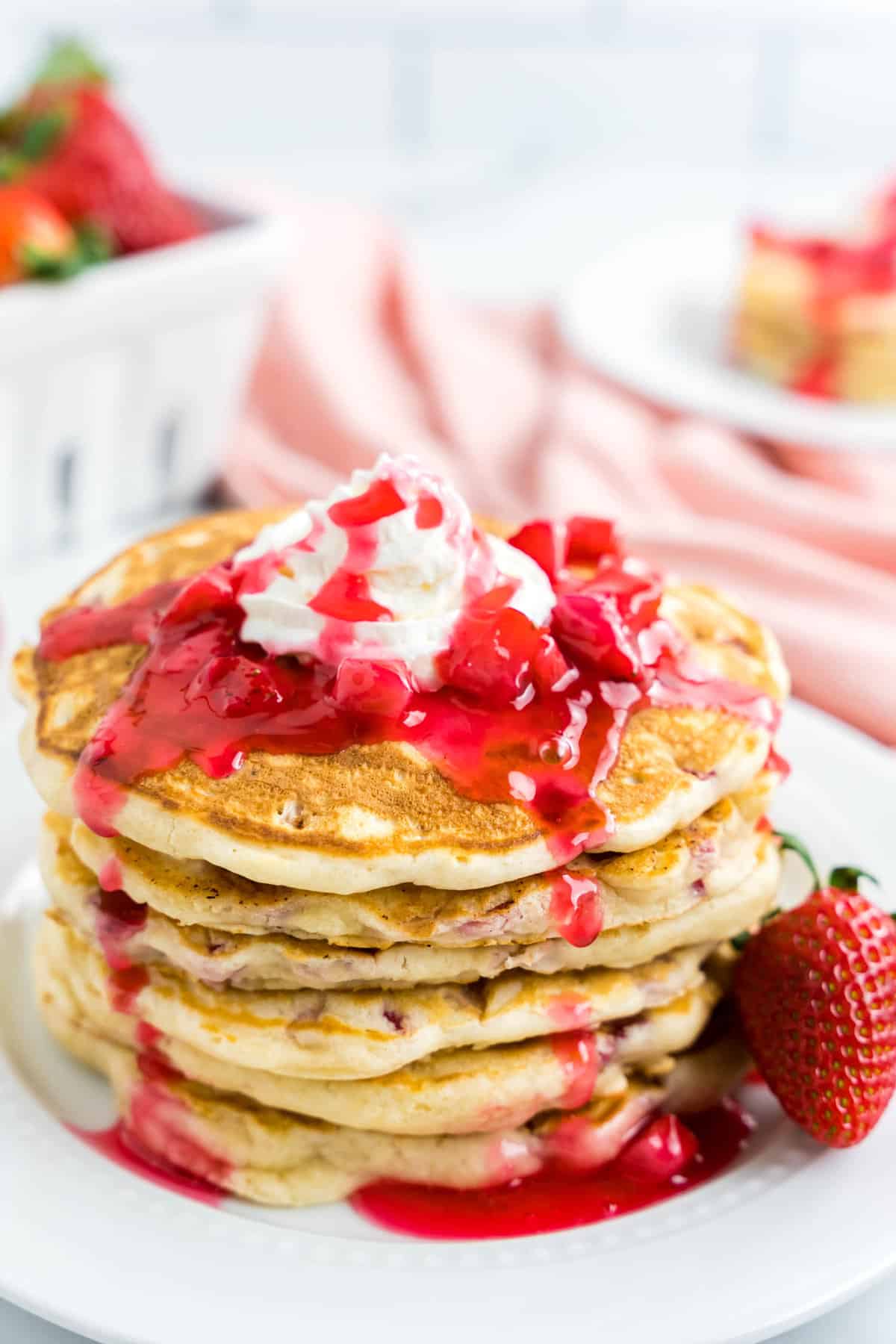 Strawberry Pancake Recipe on Plate Topped with Strawberry Syrup and Whipped Cream