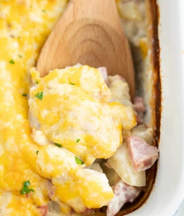 Wooden spoon scooping Ham and Potato Casserole out of dish