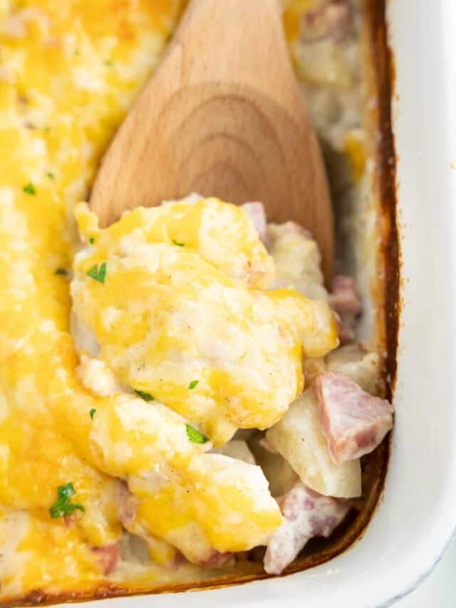 Wooden spoon scooping Ham and Potato Casserole out of dish