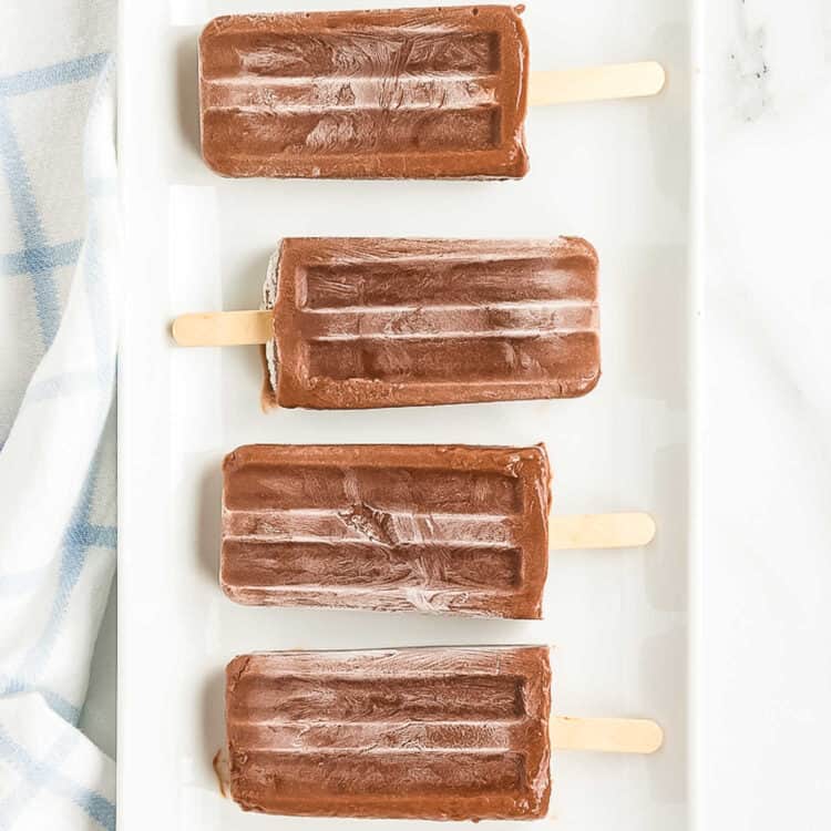 Four Fudgsicles in a row displayed on a plate.