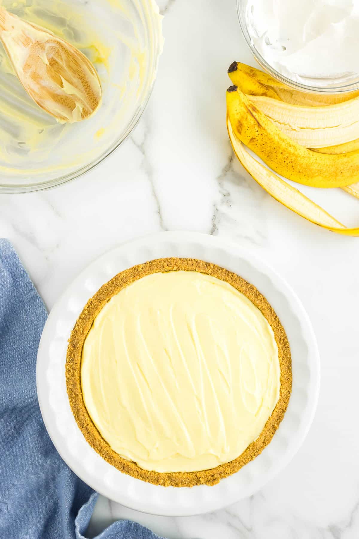 Spreading Filling in Banana-Lined Pie Crust for No Bake Banana Cream PIe Recipe