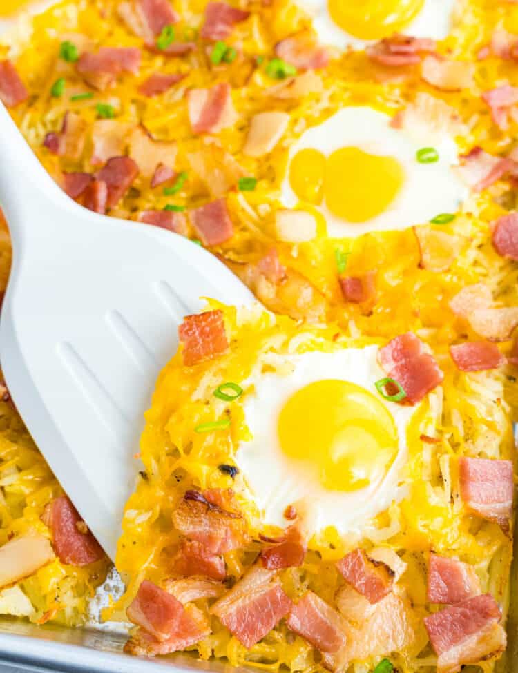 Spoon scooping an egg off a sheet pan breakfast