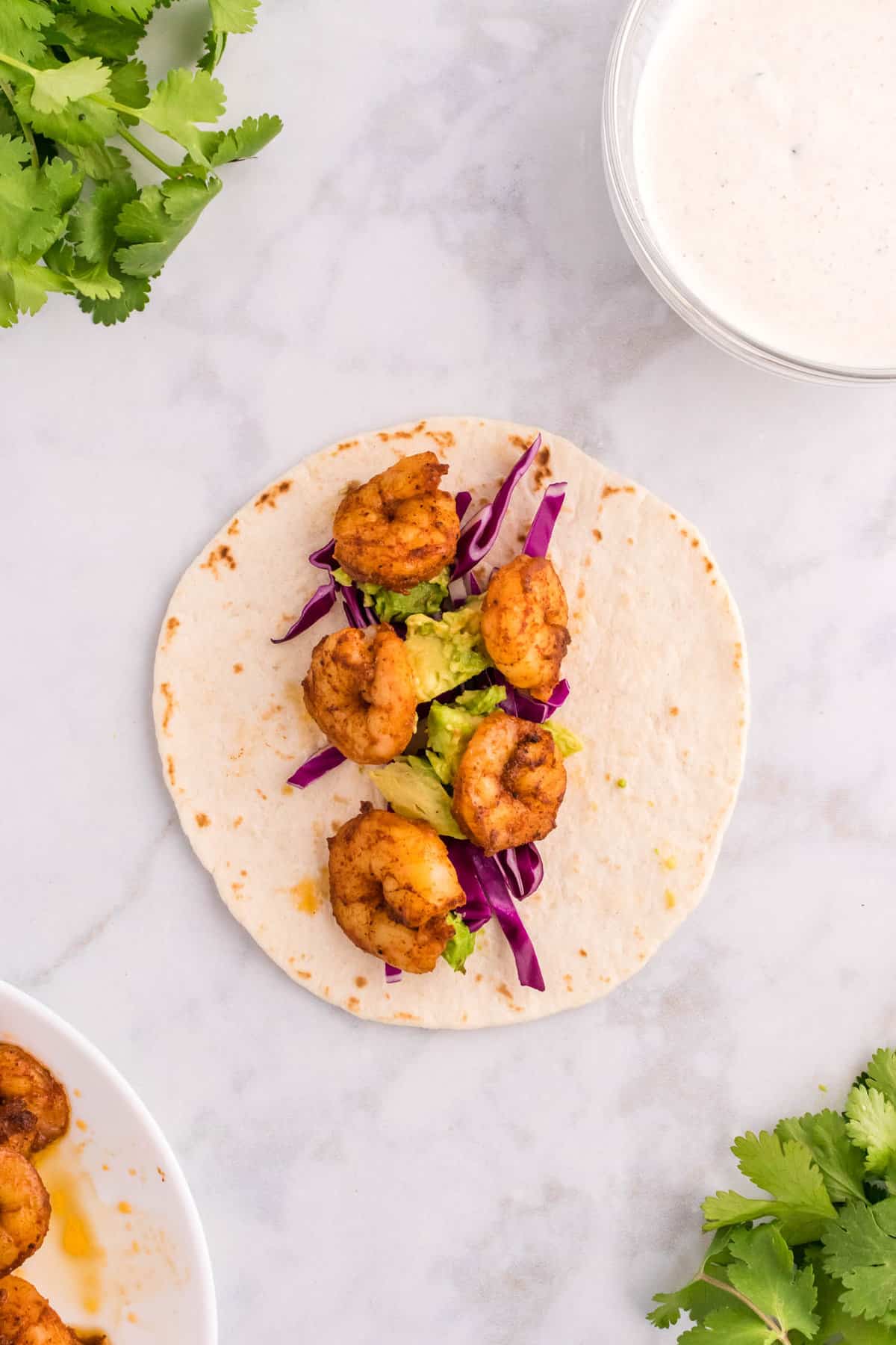 Adding Cooked and Seasoned Shrimp to Tortilla and Fixings for Shrimp Tacos Recipe