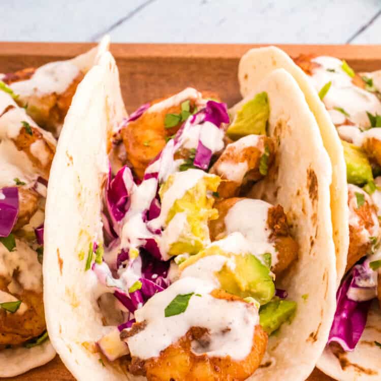 Shrimp Tacos stacked side by side on wood platter