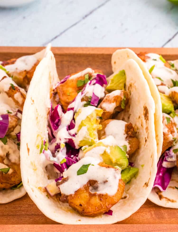 Shrimp Tacos stacked side by side on wood platter