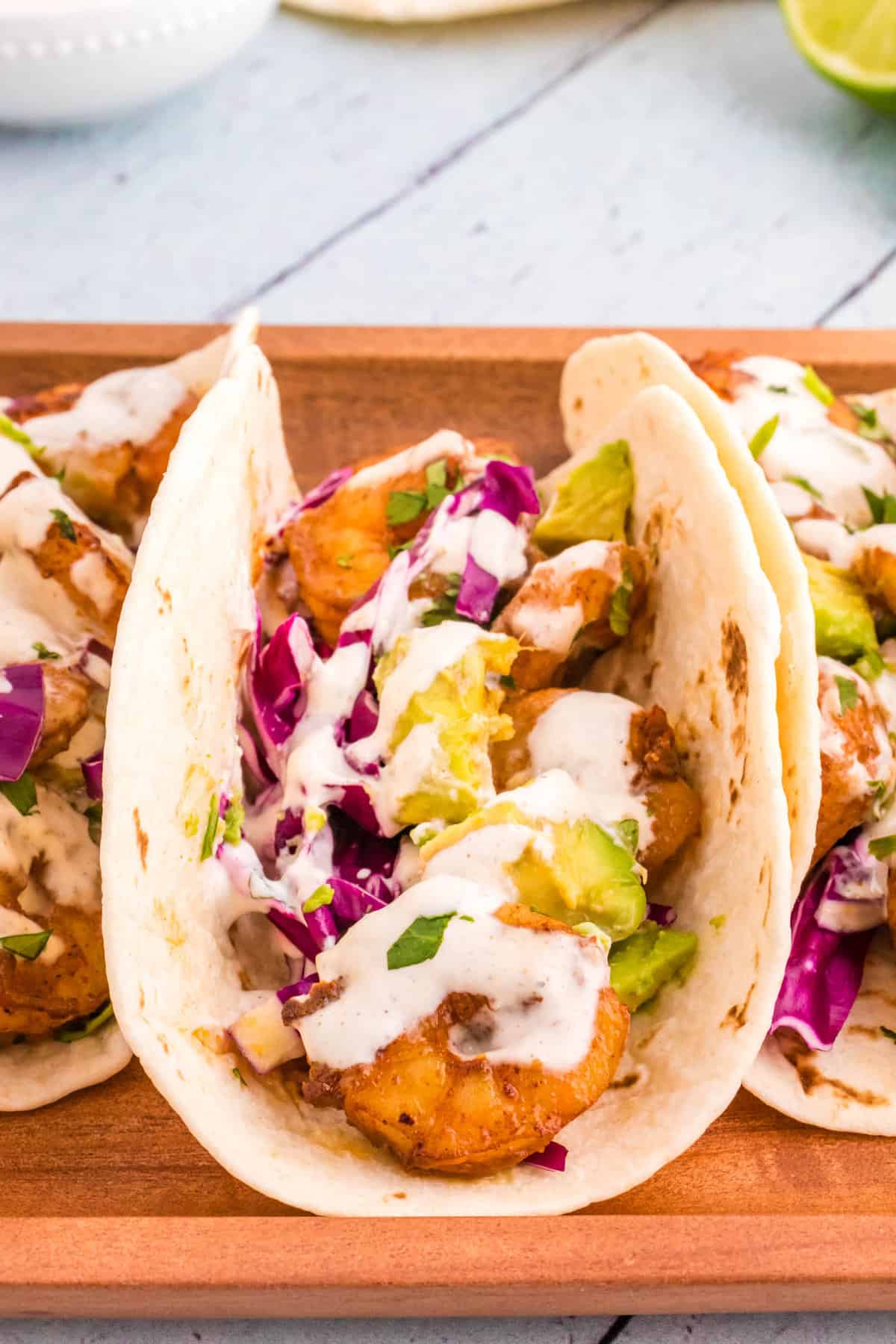 Shrimp Tacos stacked side by side on wood platter