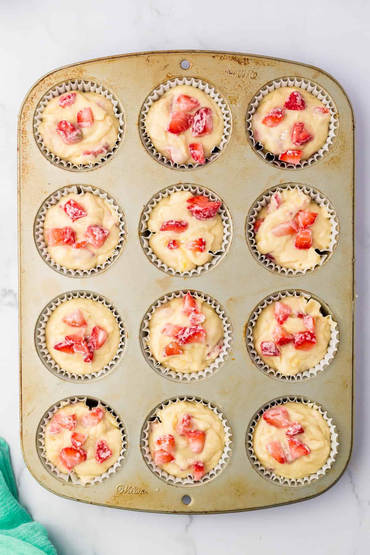 Adding More Strawberries Atop the Muffin Batter for Homemade Strawberry Muffins