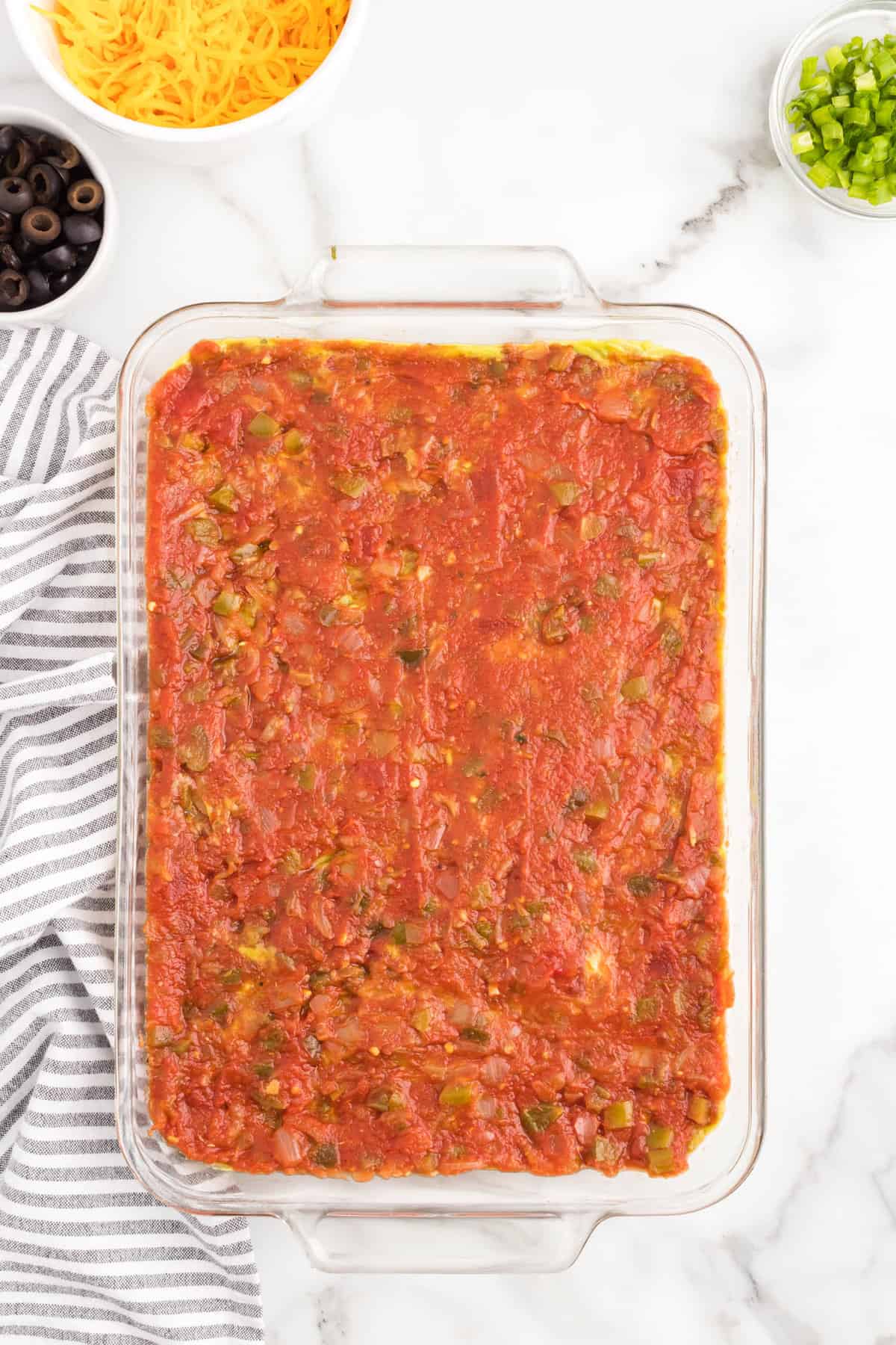 Spreading drained salsa over guacamole for 7 layer dip recipe