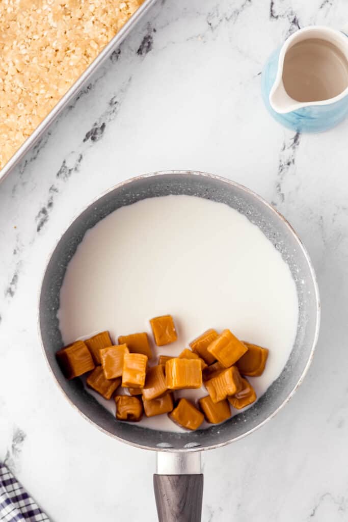 Caramels and heavy cream in stovetop pot for Caramel Oatmeal Bars