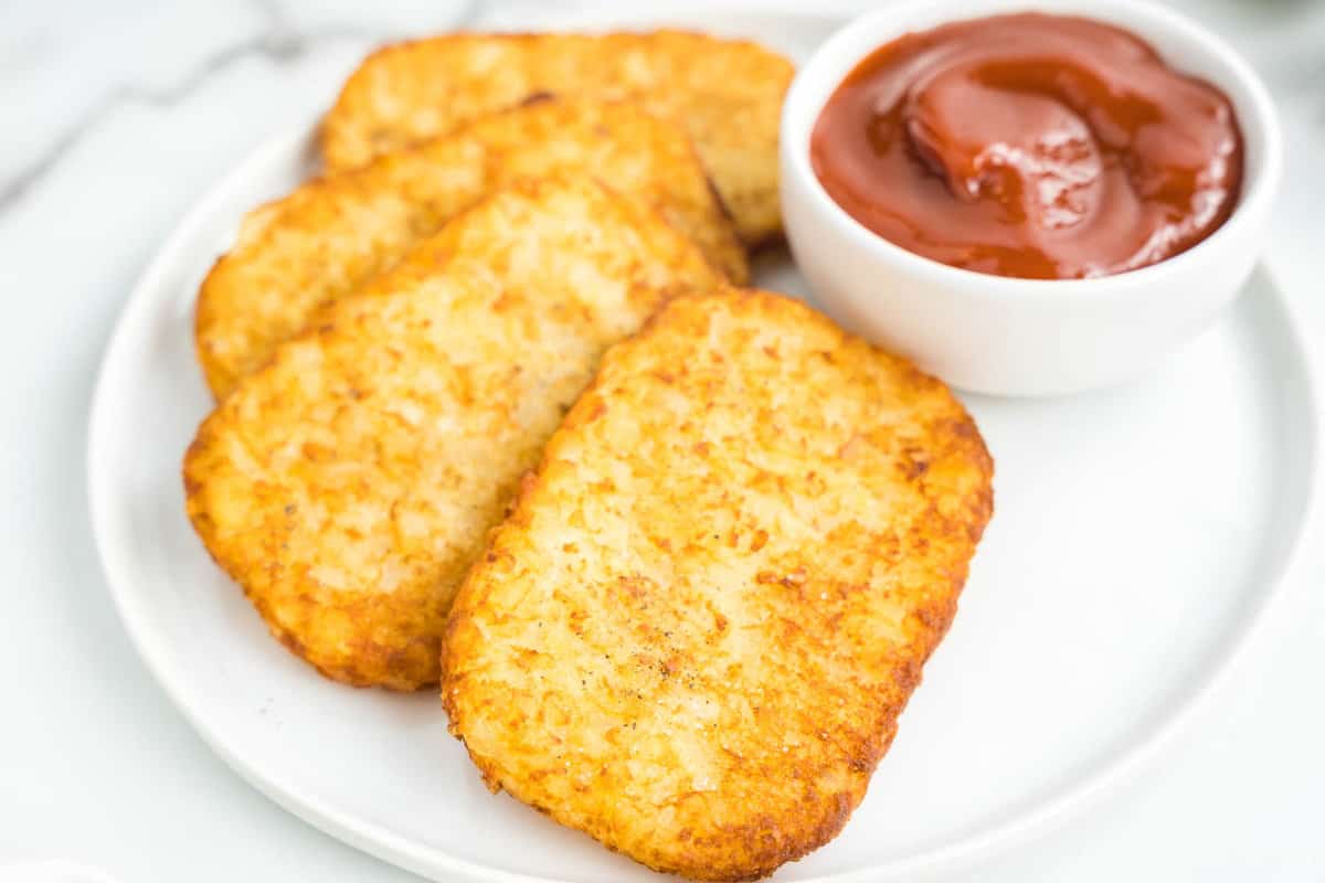 Hashbrown patties in air fryer with ketchup for dipping