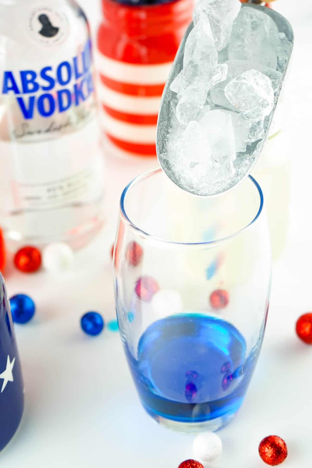 Topping Blue Curacao with ice for Red White and Blue Layered Cocktail 