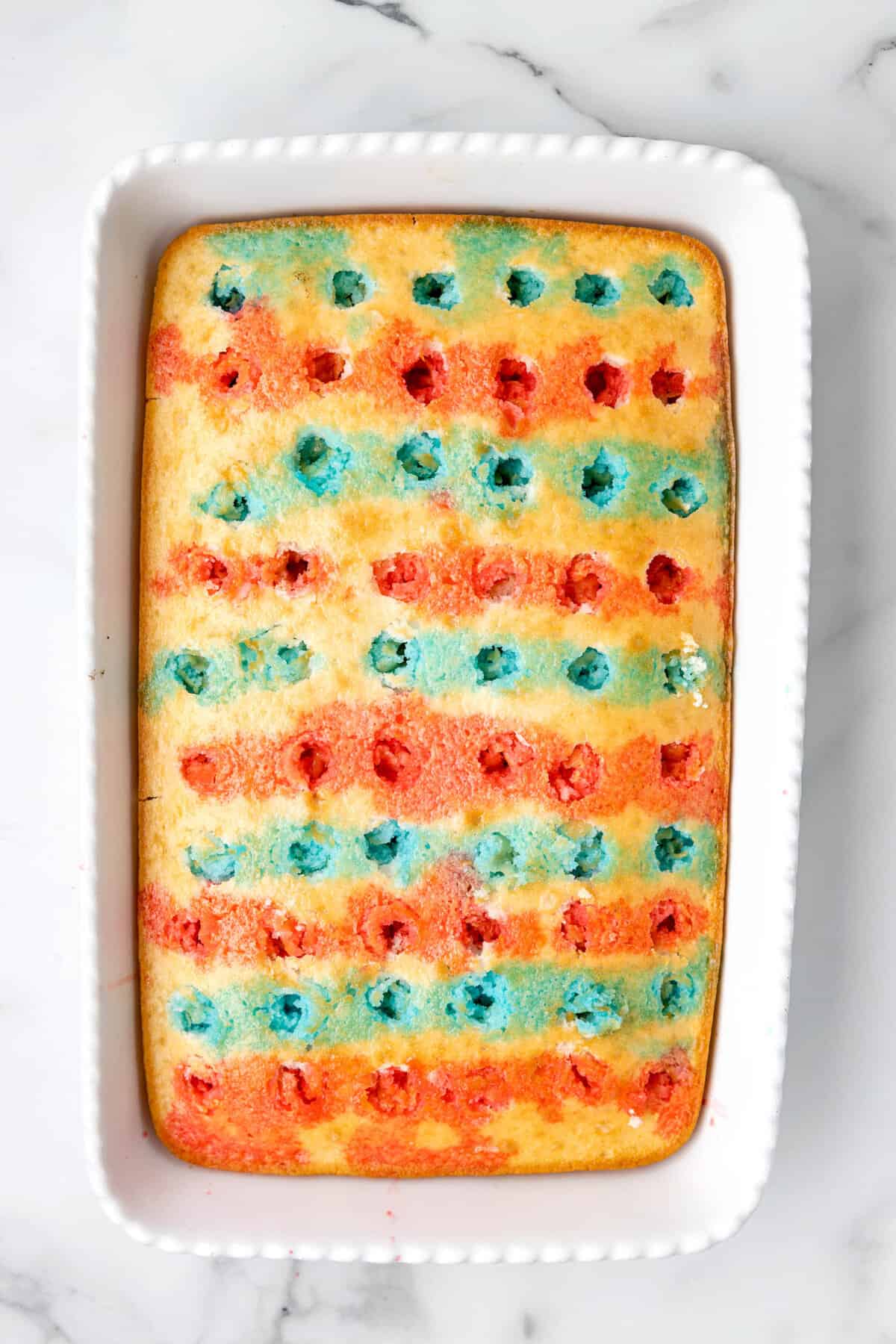 Red and blue jello in a pattern to fill holes in white cake for 4th of July Jello Cake recipe