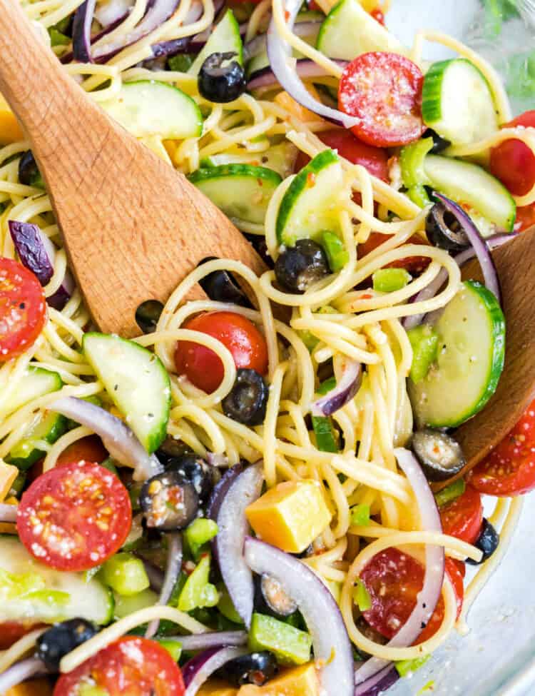 Tossing Spaghetti Salad in bowl with wooden spoon