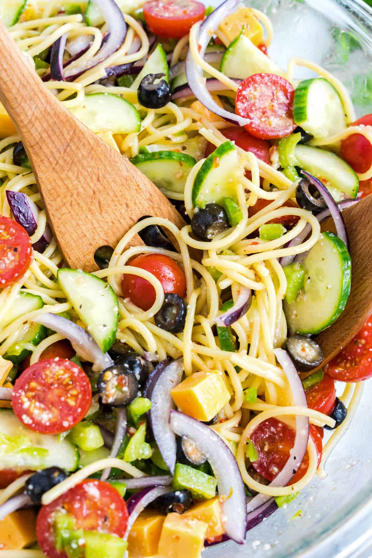 Tossing Spaghetti Salad in bowl with wooden spoon