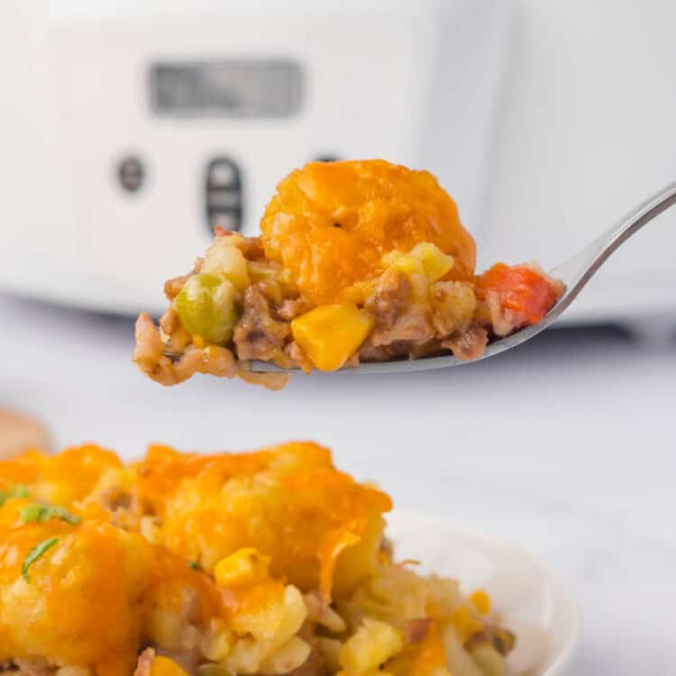 Crock Pot Tater Tot Casserole Recipe on Plate with a Forkful Ready to Enjoy with Crock Pot in Background