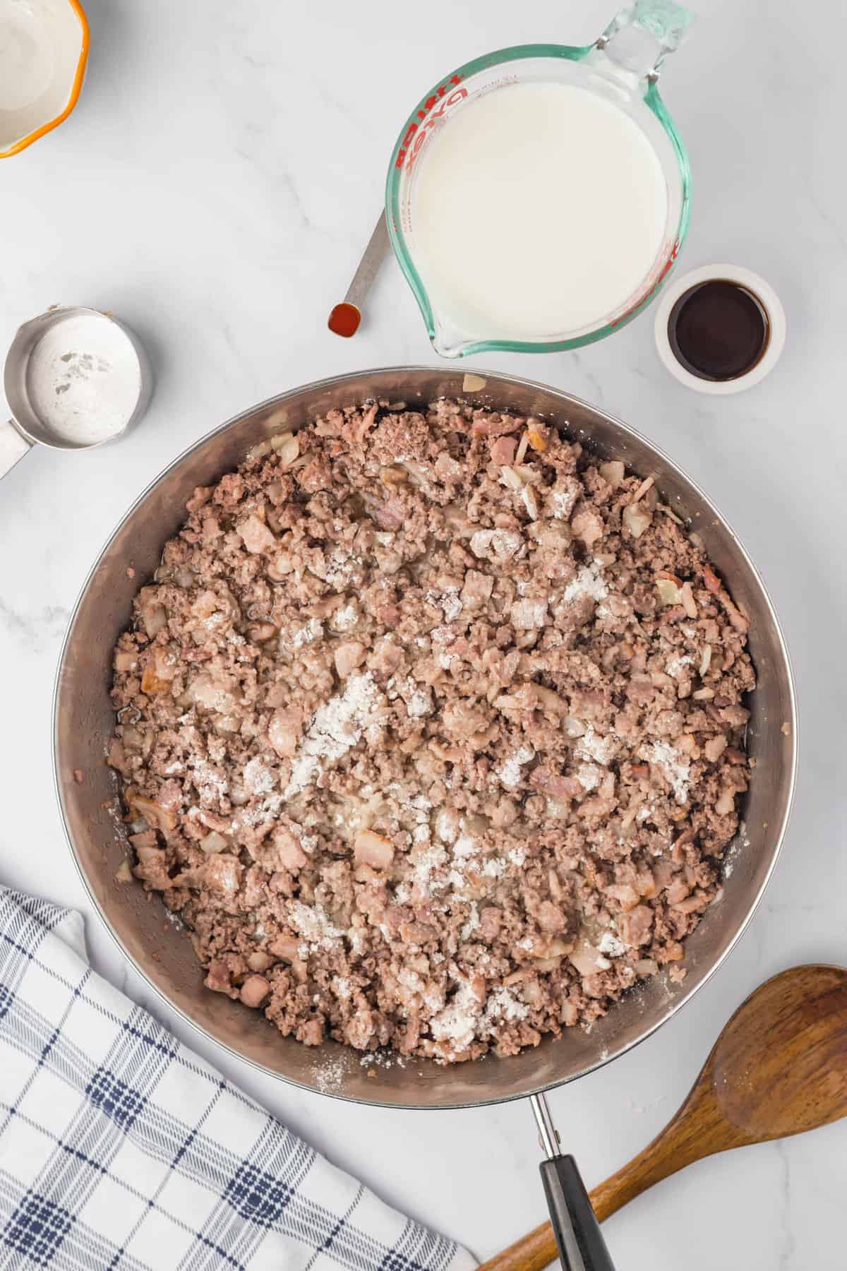 Adding flour to browned meat mixture to ticken for Bacon Cheeseburger Crock Pot Tater Tot Casserole Recipe