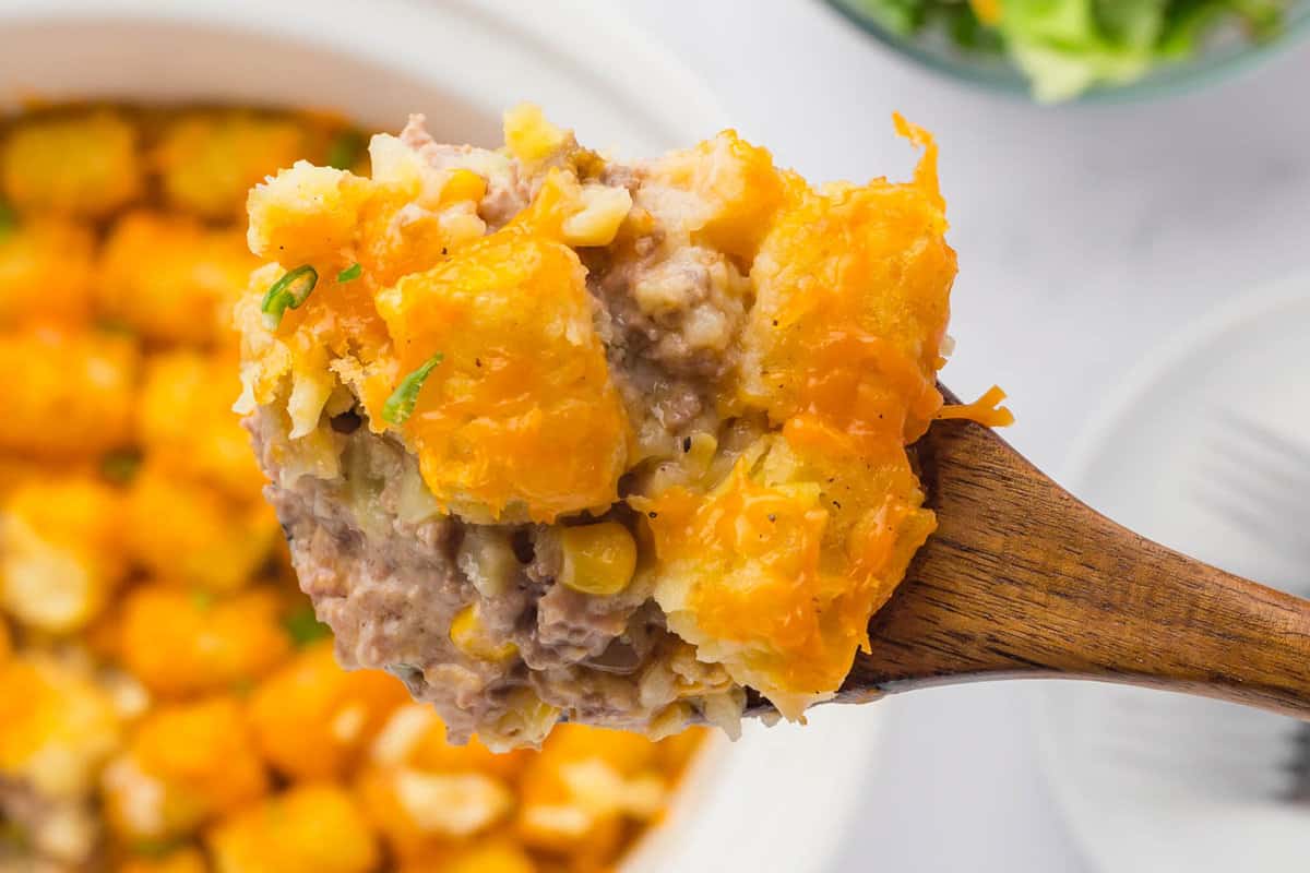Slow Cooker Tater Tot Casserole with Wooden Spoon with an Overflowing Scoop Hot ouf of the Crock Pot