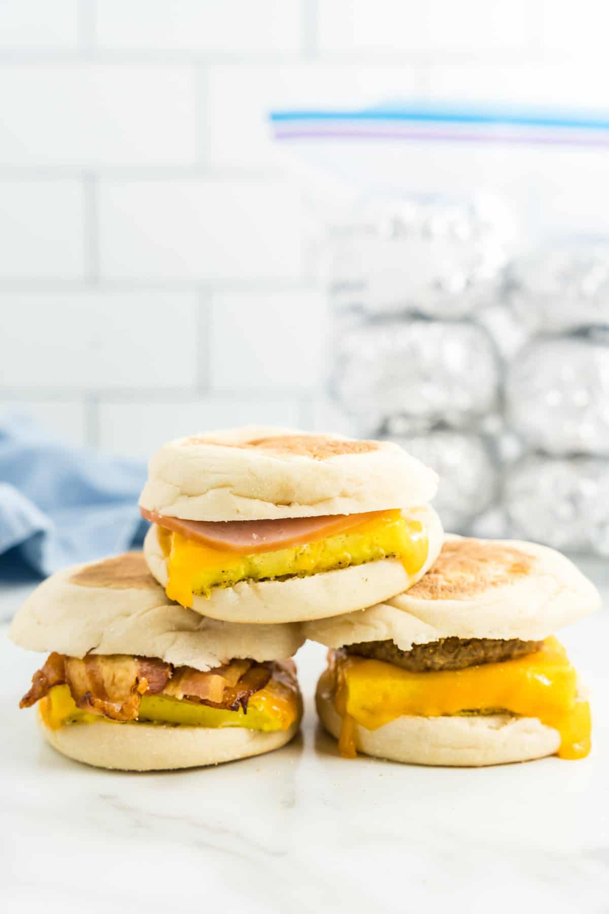 Freezer Breakfast Sandwiches with a Variety of Meats Stacked with Freezer Sandwiches in Tinfoil