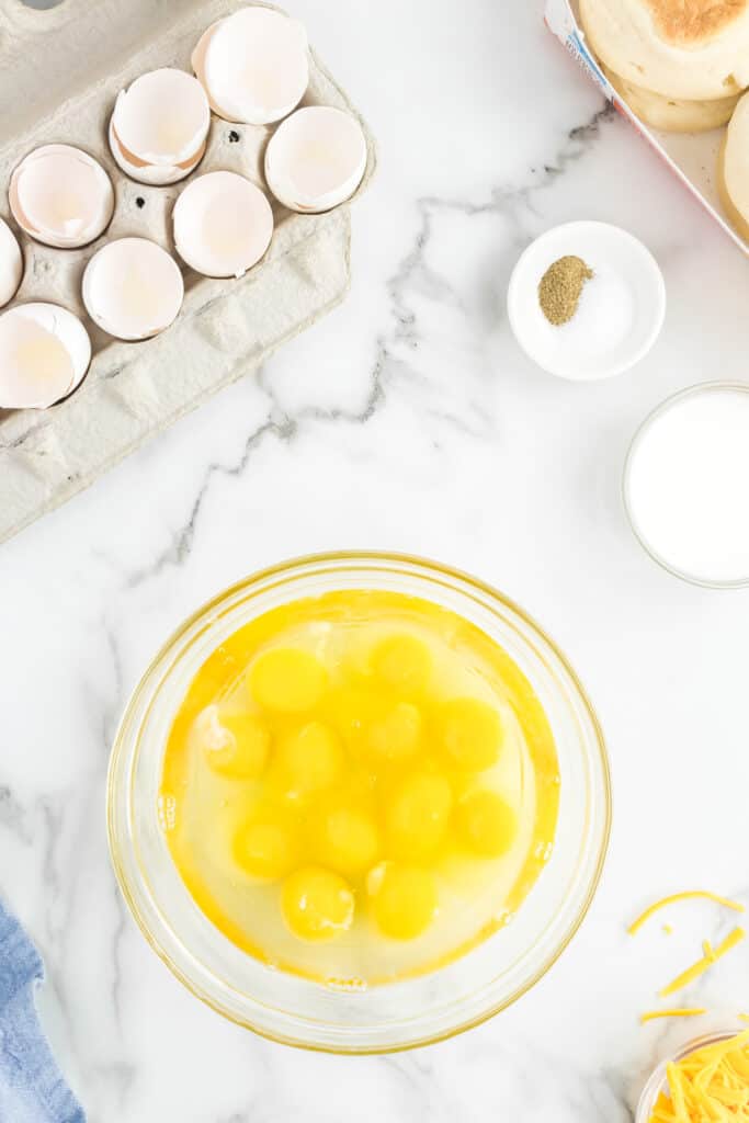 One dozen eggs in mixing bowl for Freezer Breakfast Sandwiches Recipe