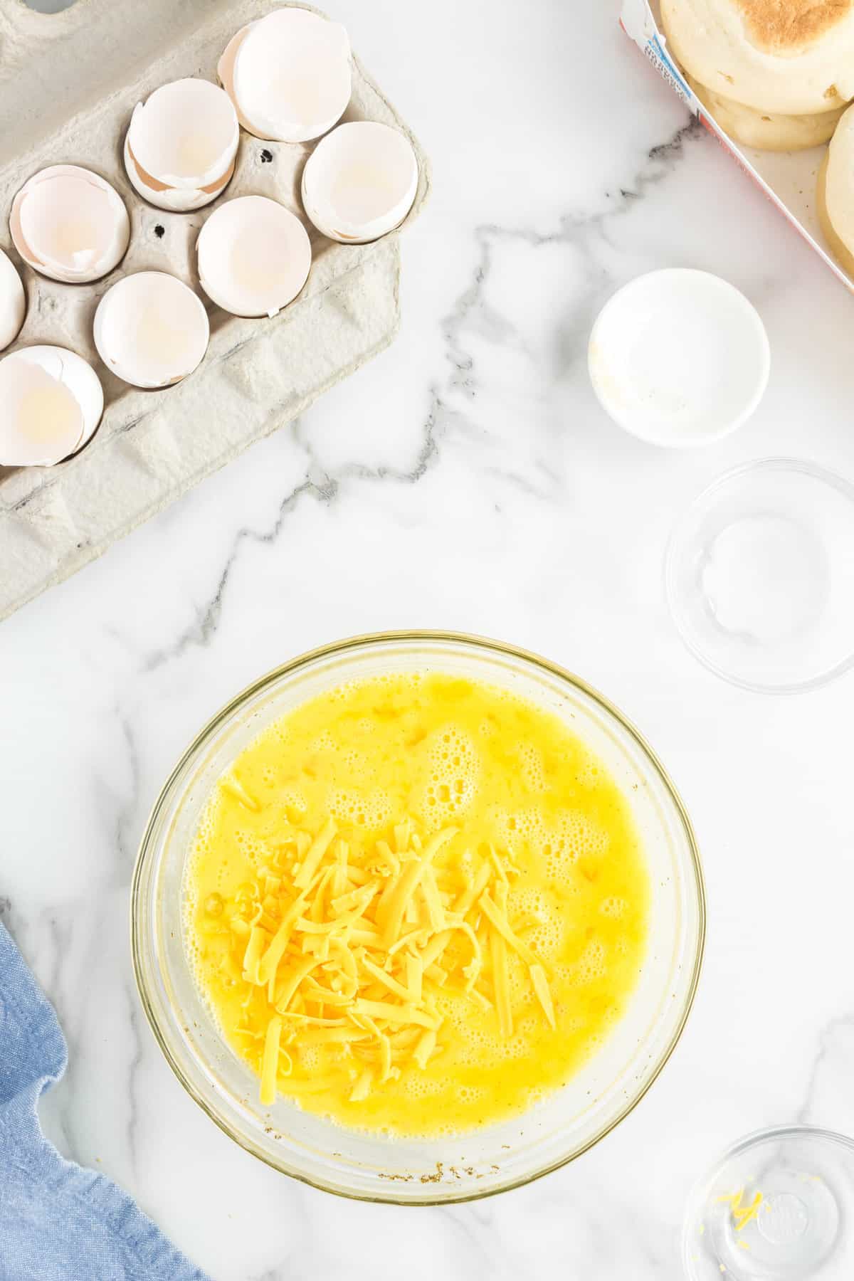 Stirring in cheese for Meal Prep Breakfast Sandwiches in mixing bowl