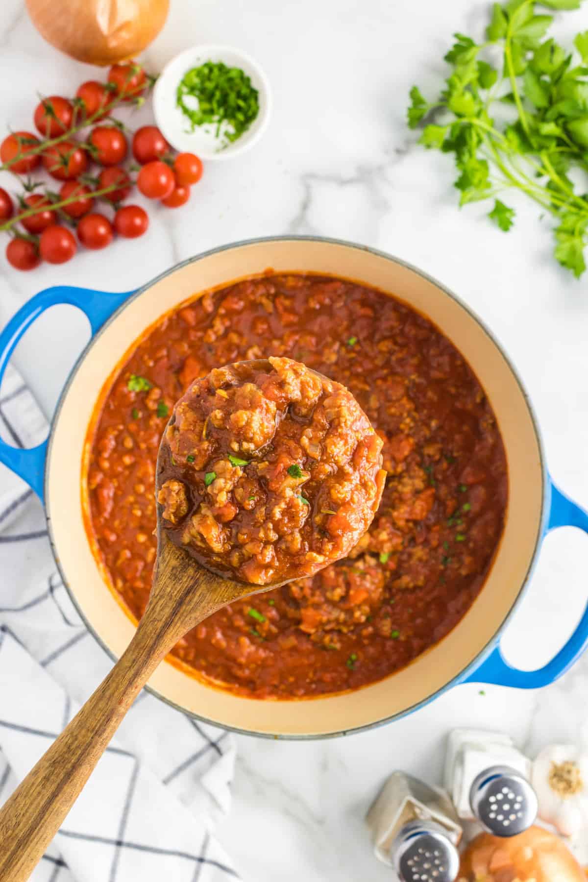 Using a wooden spoon to scoop out Homemade Spaghetti Sauce from pot