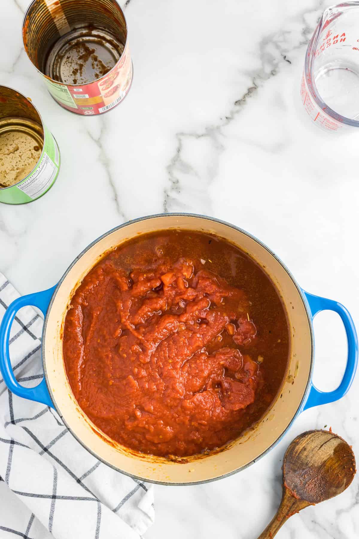 Adding diced tomato sauces to mixture in stovetop pot