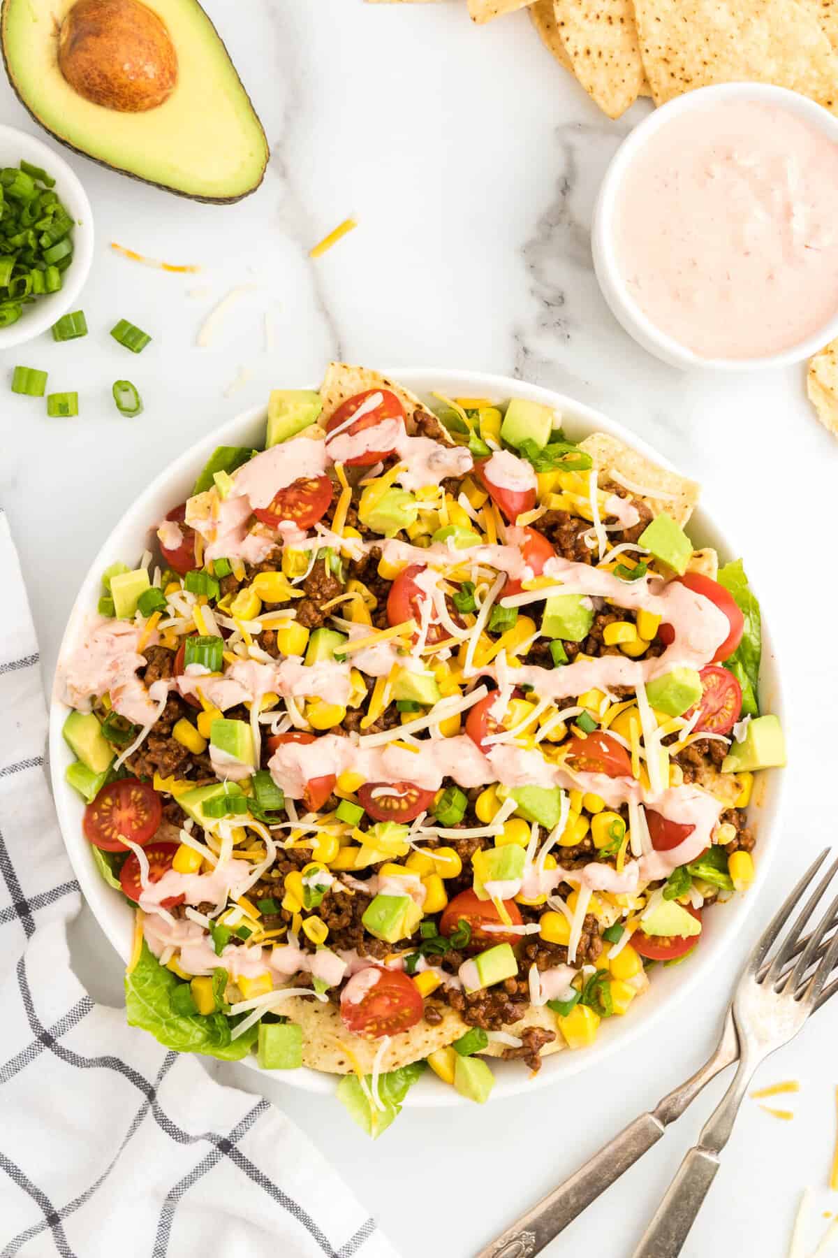 Drizzling sour cream salsa mixture atop taco salad in bowl