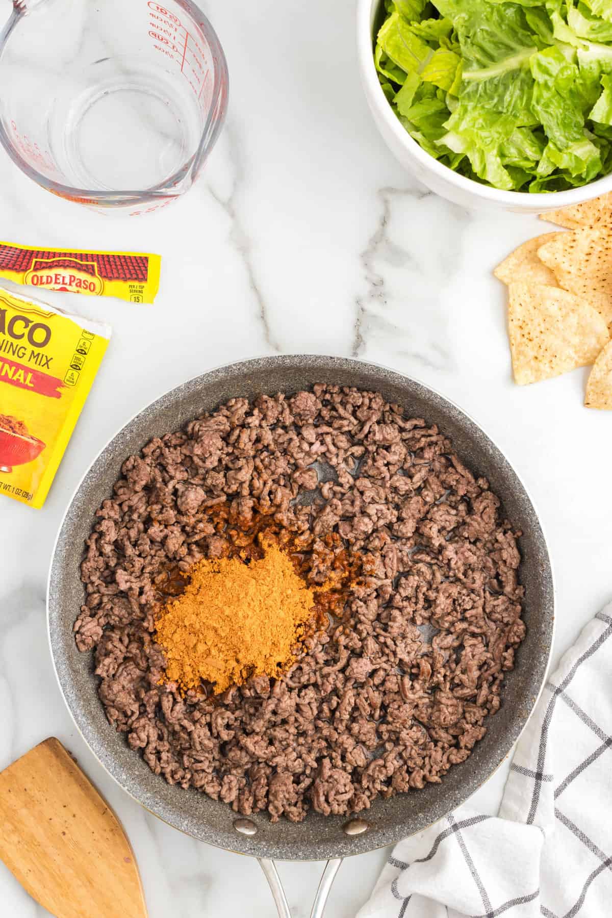 Ground beef, water, and taco seasoning in stovetop skillet for Taco Salad Recipe