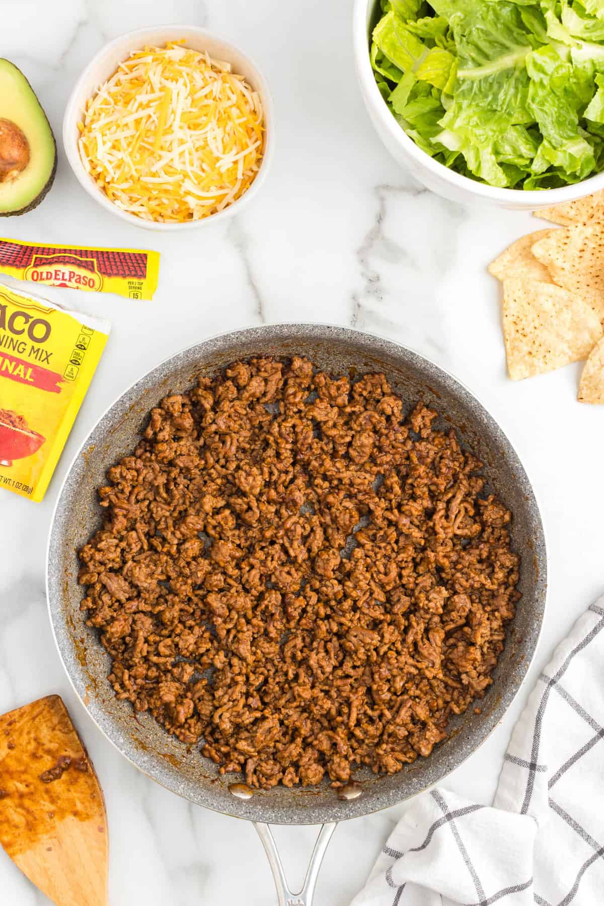 Ground beef, water, and taco seasoning in stovetop skillet for Taco Salad Recipe