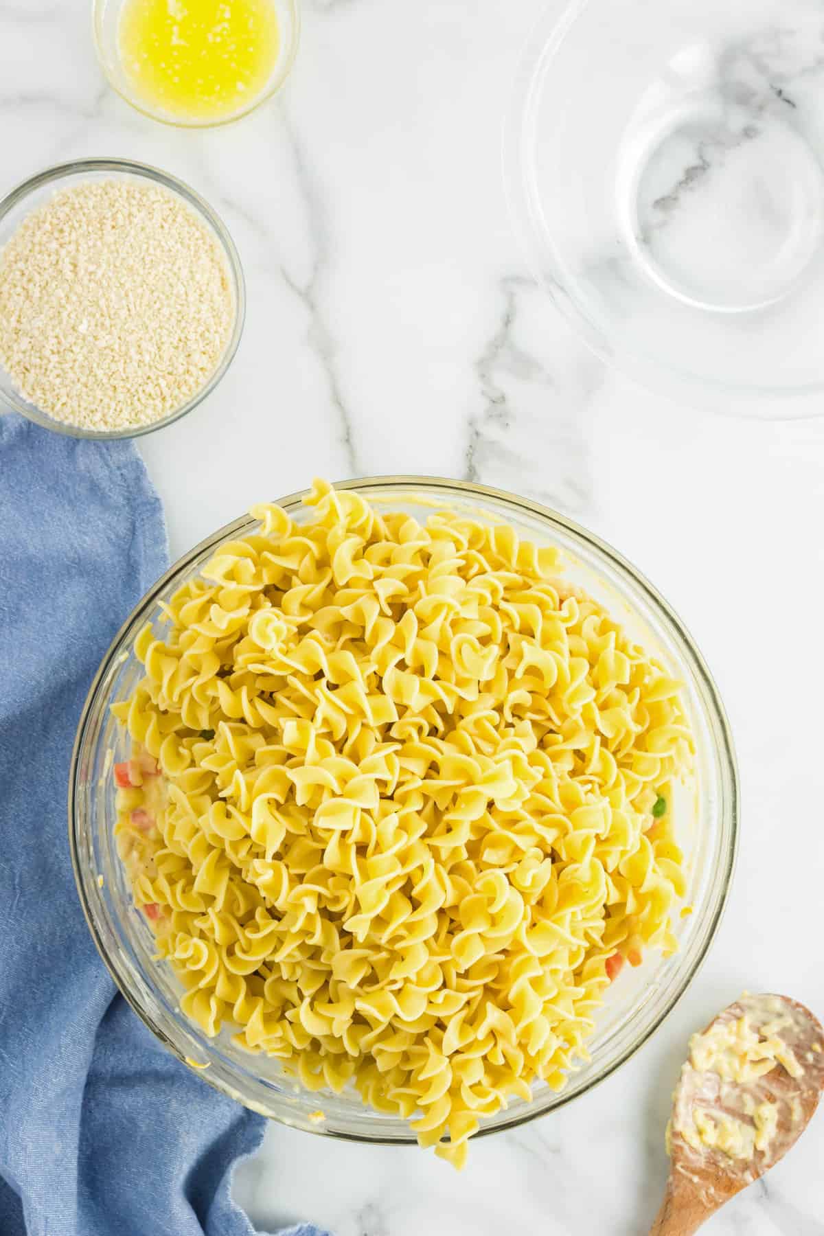 Adding cooked egg noddles to ingredients in mixing bowl for Chicken Noodle Casserole Recipe