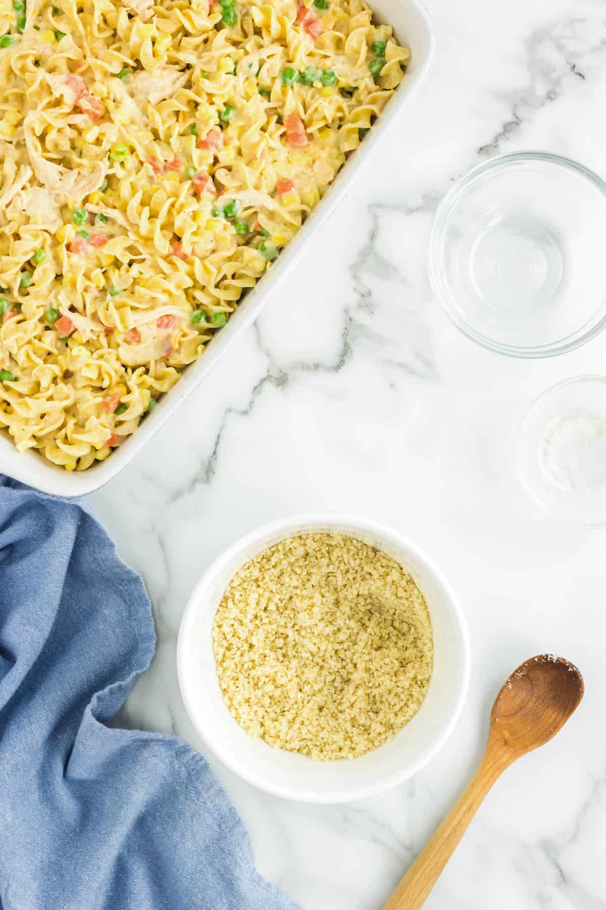 Topping Chicken Noodle Casserole with panko crumbs in glass baking dish