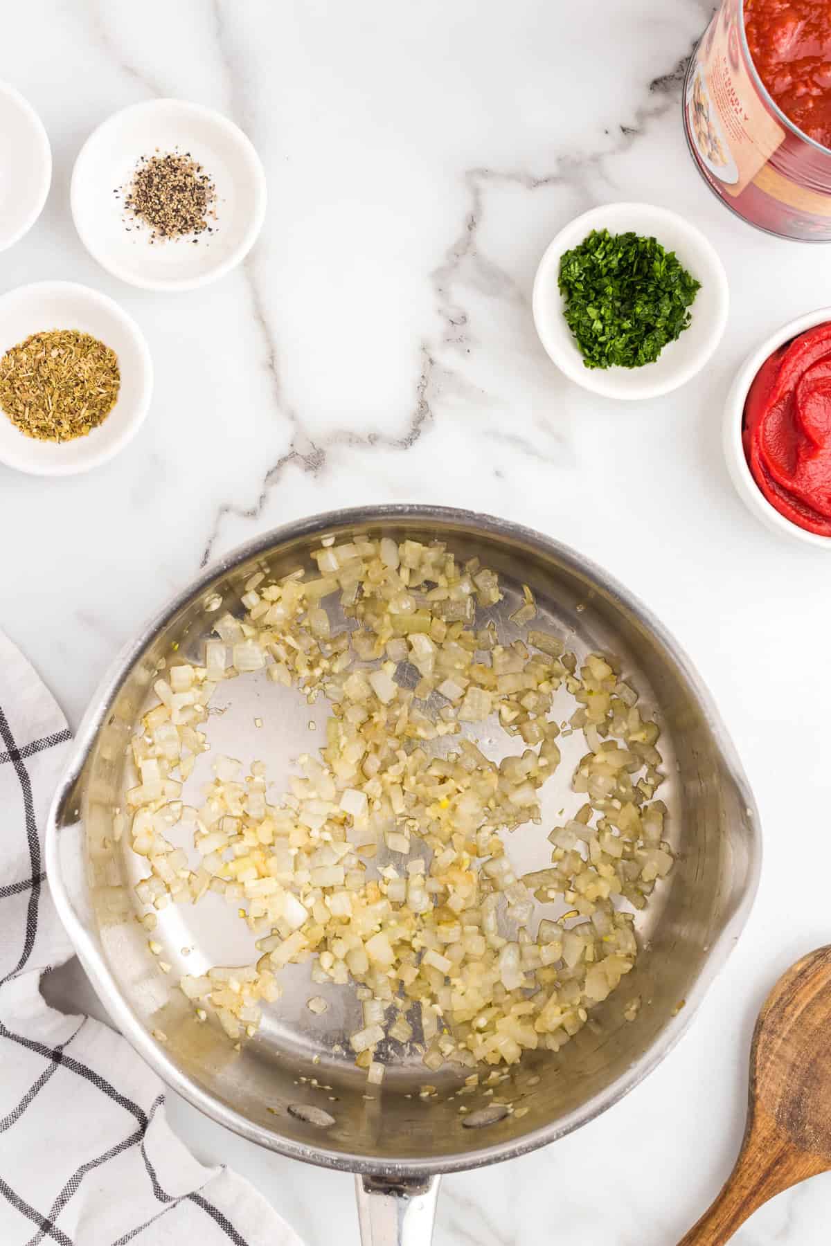 Cooking onions and garlic in stovetop pan with olive oil until fragrant and tender for Homemade Marinara Sauce recipe